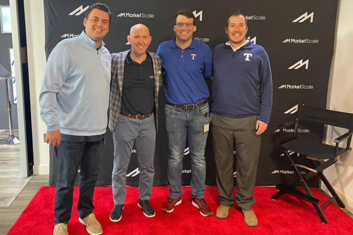 Patrick Rishe (second from left), director of the Sports Business Program at WashU, poses with three members of the Texas Rangers' front office -- all WashU alumni. From left, Zack Kessinger, Sam Linker and Alexander Booth.