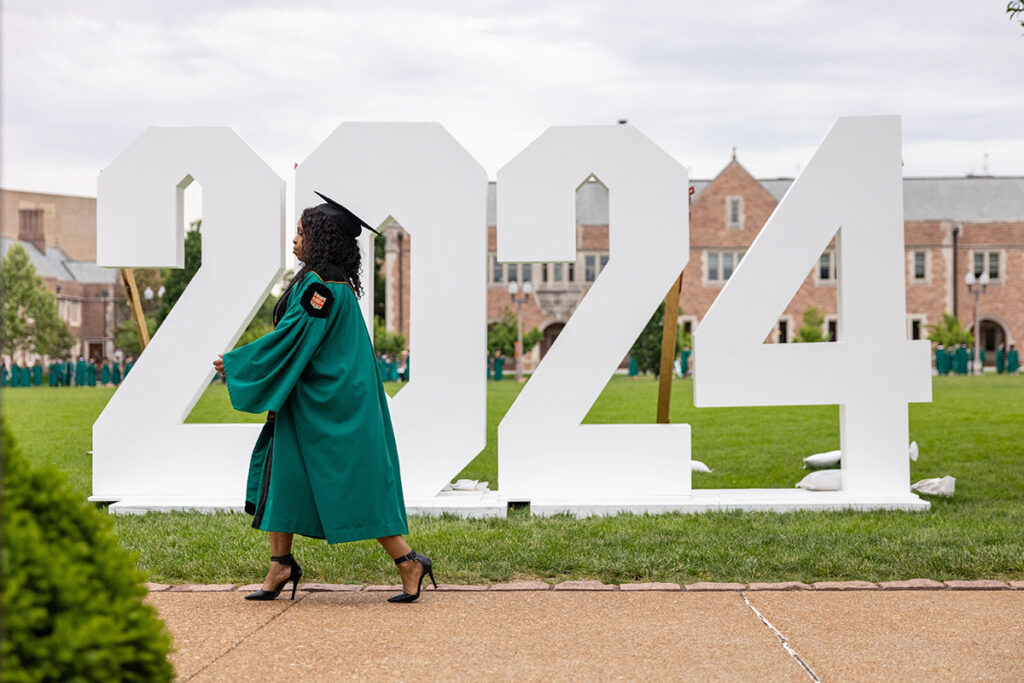 Graduate walks past 2024 sign